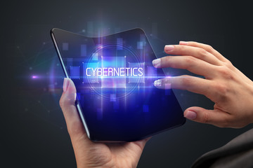 Businessman holding a foldable smartphone with CYBERNETICS inscription, new technology concept