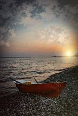 Red boat on the shingle beach of Sochi. Sunset.