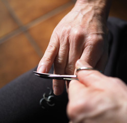 Manos de hombre cortándose las uñas.