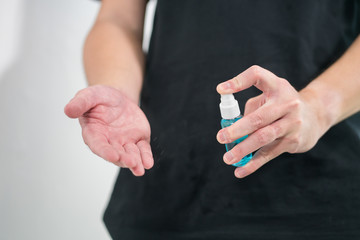 Close-up male hand pushing plastic bottle spray with alcohol hand gel. Coronavirus or covid 19 concept.