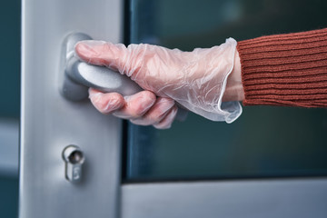 Person in transparent protective gloves holds handle during flu covid outbreak and infectious...