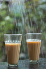 Glasses of chai in front of rainy window glass
