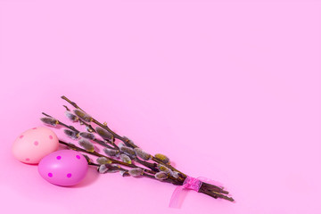 Two pink polka-dot eggs lie next to willow branches on a pink background. View from above. place for text. Banner Easter card. Easter background. Easter.