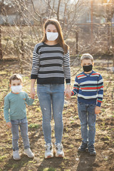 A loving mother holds and hugs her children. They wear protective masks against the virus.