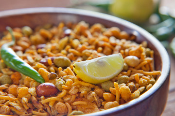 Close-up of fried mixture in a bowl with slice of lemon and green chilies
