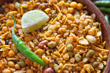 Close-up of fried mixture in a bowl with slice of lemon and green chilies
