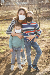 A loving mother holds and hugs her children. They wear protective masks against the virus.
