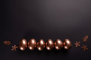 Row of gold Easter eggs on black background. Flat lay, Top view, copy space. Miniml easter concept