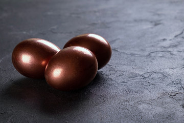 Easter minimal background with gold Easter eggs on black background. Copy space.