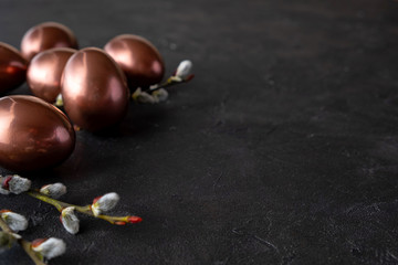 Easter composition with eggs and twigs of willow blossom. minimal background with gold Easter eggs on black background. Copy space.