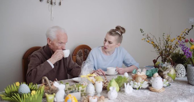 Happy Easter - Senior Man and Young Woman Drinking Tea during Easter Holidays