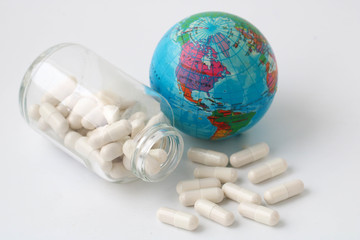 small blue world ball next to white capsules with granules inside on the white background