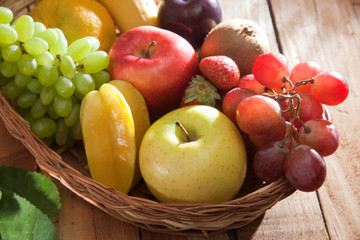 Wicker basket filled with fresh fruits against wooden background