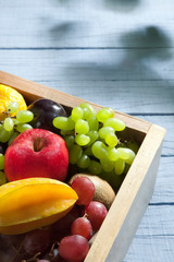 Fresh fruits in vintage crate on whitewashed wooden table