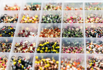 tungsten jig-hooks of different colors, shapes and weights in a box for winter fishing