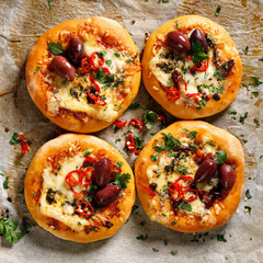 Small homemade pizzas on a baking parchment  background, top view