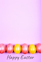 Easter eggs painted in yellow and pink colors on pink background.