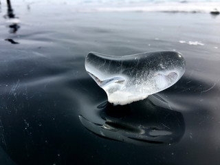 a figure of transparent ice on the surface of a frozen lake