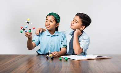 Indian school boy and girl or science student in uniform Using Molecular Model Kit for studying physics, selective focus - Powered by Adobe