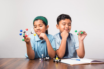 Indian school boy and girl or science student in uniform Using Molecular Model Kit for studying...