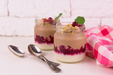  Two servings of chocolate-vanilla pudding with berries and a jar on a white background.