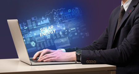 Businessman working on laptop with SOLAR ENERGY inscription, cyber technology concept