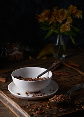 Chocolate granola in white bowl. Dark key photo style. cozy home, homemade breakfast