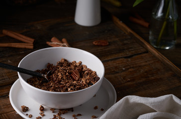Chocolate granola in white bowl. Dark key photo style. cozy home, homemade breakfast