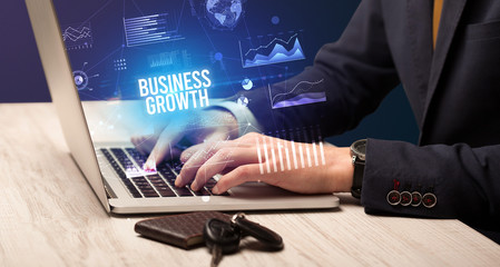 Businessman working on laptop with BUSINESS GROWTH inscription, new business concept