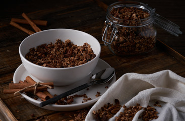 Chocolate granola in white bowl. Dark key photo style. cozy home, homemade breakfast