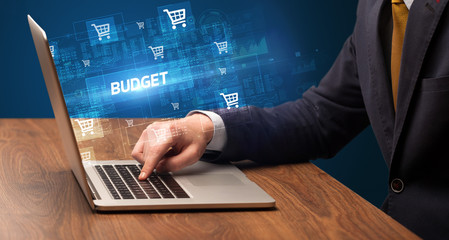 Businessman working on laptop with BUDGET inscription, online shopping concept