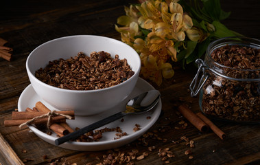 Chocolate granola in white bowl. Dark key photo style. cozy home, homemade breakfast