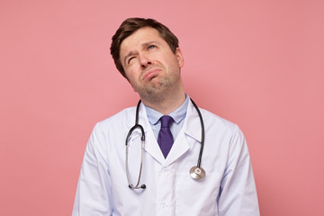 A middle aged male doctor feeling angry and tired in white coat and stethoscope