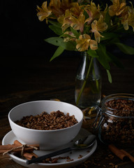 Chocolate granola in white bowl. Dark key photo style. cozy home, homemade breakfast