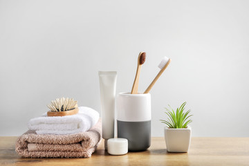Wooden toothbrushes, dentifrices, bath towels and hairbrush on wooden surface on white background