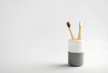 Wooden toothbrushes in cup on white background