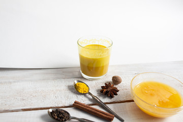 Golden milk ayurvedic drink with honey, turmeric, spices on white background