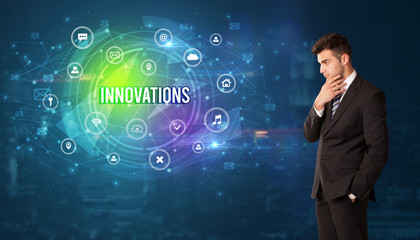 Businessman thinking in front of technology related icons and INNOVATIONS inscription, modern technology concept