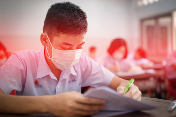 The Asian high school students in a white school uniform wearing the masks to do final exams in the midst of Coronavirus disease 2019 (COVID-19) epidemic and PM 2.5.