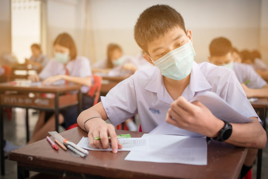 The Asian high school students in a white school uniform wearing the masks to do final exams in the midst of Coronavirus disease 2019 (COVID-19) epidemic and PM 2.5.