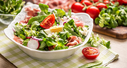 Fresh spring salad with green leaves tomatoes egg radish red onion young peas prosciutto feta...