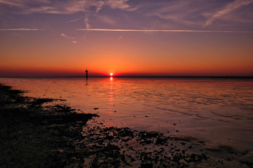 Dynamic golden sunset behind low hanging clouds over the north sea at the Dutch coast. Golden color, The Wadden Sea is a UNESCO World Heritage Site, Moddergat, the Netherland