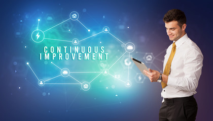 Businessman in front of cloud service icons with CONTINUOUS IMPROVEMENT inscription, modern technology concept