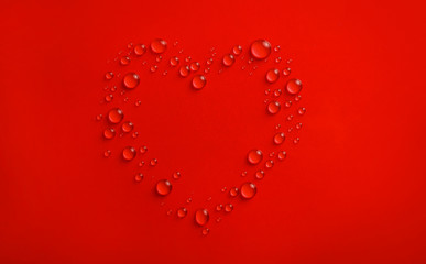 Water drops in shape of heart on red background