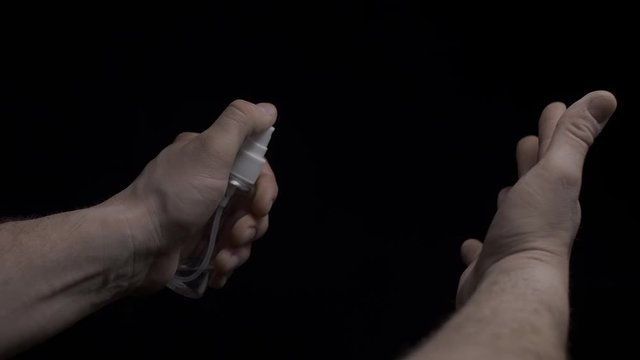 Man sprays antiseptic liquid on his hands in 4K slow motion