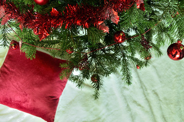 Fototapeta na wymiar Christmas Tree with red Ornaments and a red Fluffy Pillow