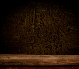 Empty, free, wooden table in front of an abstract dark wall background. Can be used to display or edit your products.