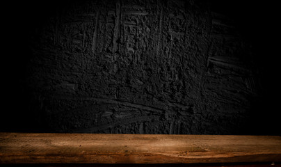 Empty, free, wooden table in front of an abstract dark wall background. Can be used to display or edit your products.