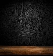 Empty, free, wooden table in front of an abstract dark wall background. Can be used to display or edit your products.
