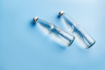 Glass water bottles on blue background
